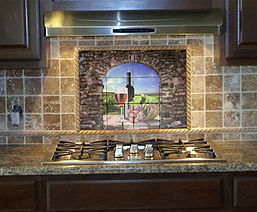 Tile mural with wine bottle and glass scene above kitchen stovetop