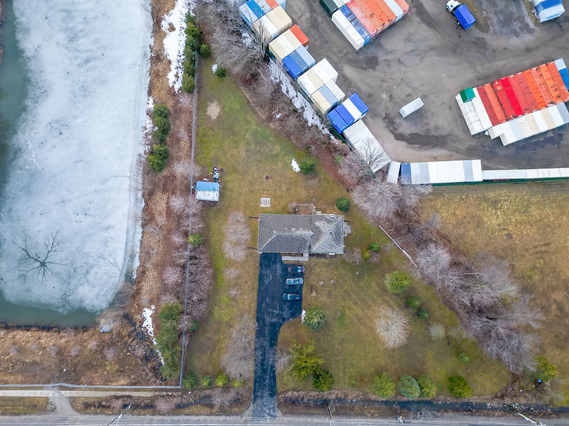 Aerial view of a house by an icy pond next to shipping containers