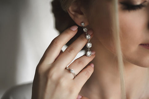 Woman wearing diamond dangle earrings and a ring
