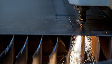 Laser cutting structural steel with sparks flying.