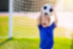 Happy boy holding soccer ball above his head