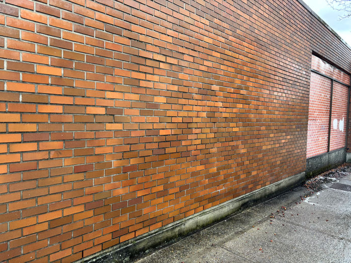 Red brick building exterior wall along a sidewalk