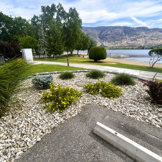 Landscaped gravel garden by a lake and mountains.