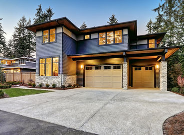 Modern blue two-story house with stone accents and two garage doors.