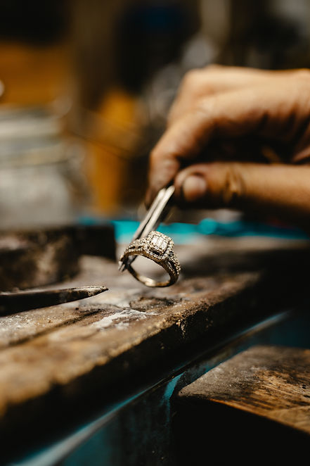 Jeweler's hand inspects an ornate ring on a workbench