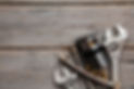 Plumbing tools including wrenches, flexible pipe, and drain assembly on wood.