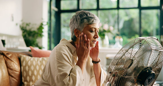 Woman experiencing menopause symptoms and hot flushes at home