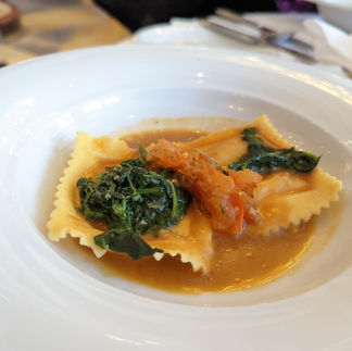 A plate of ravioli with spinach and tomato sauce. 