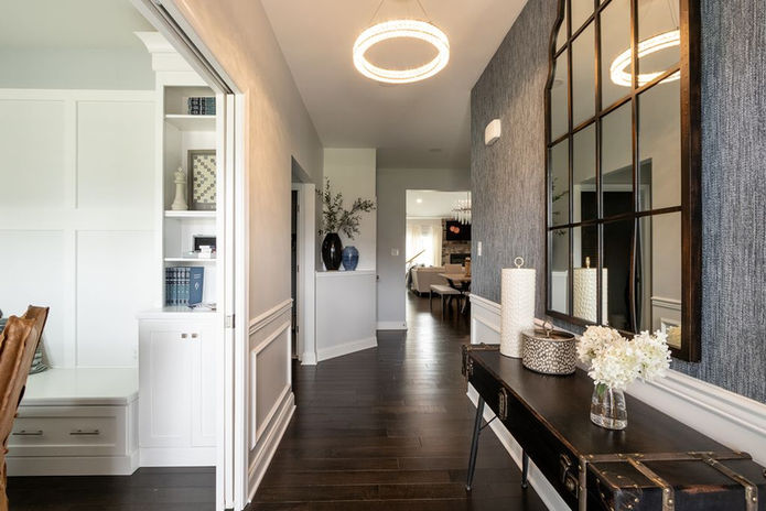 Entryway with navy blue grass cloth walls, 5 foot tall mirror and console table, crystal light fixture. You can see the grand living area in front of you.