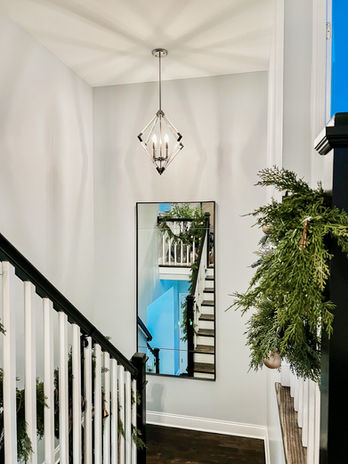 Interior design by Souled Home Design.  Black railing with white spindles look crisp with the Maxim Lighting crystal light pendant and oversized steel mirror from Pottery Barn.