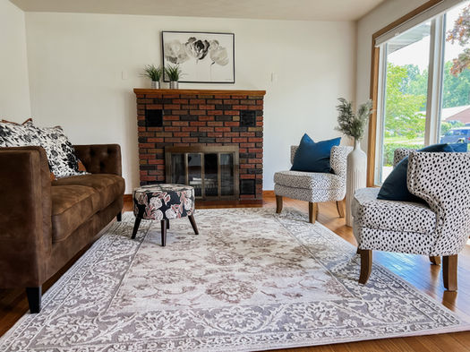 This living room was staged by Souled Home Design.  The chocolate velvet sofa and white chairs with black polka dots create a modern feel in this classic home with the original wood floors.