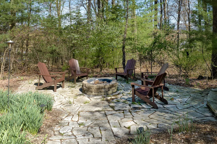 Stone patio and Fire pit surrounded with brown adirondack chairs