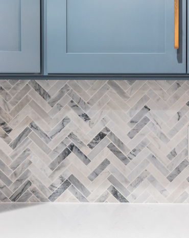 Mosaic grey and white herringbone tile backsplash with blue kitchen cabinet,