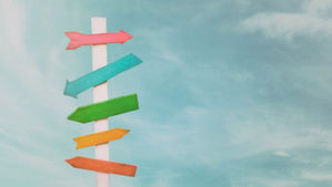 A multi colored signpost with signs pointing in many directions