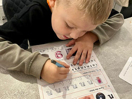 "Close‑up of a child’s hand using the Early Learner Box — mapped support for writing first letters with a chunky pencil on paper.