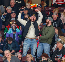 Two adult men celebrating after catching a t-shirt during a t-shirt toss at an Oshawa Generals game.