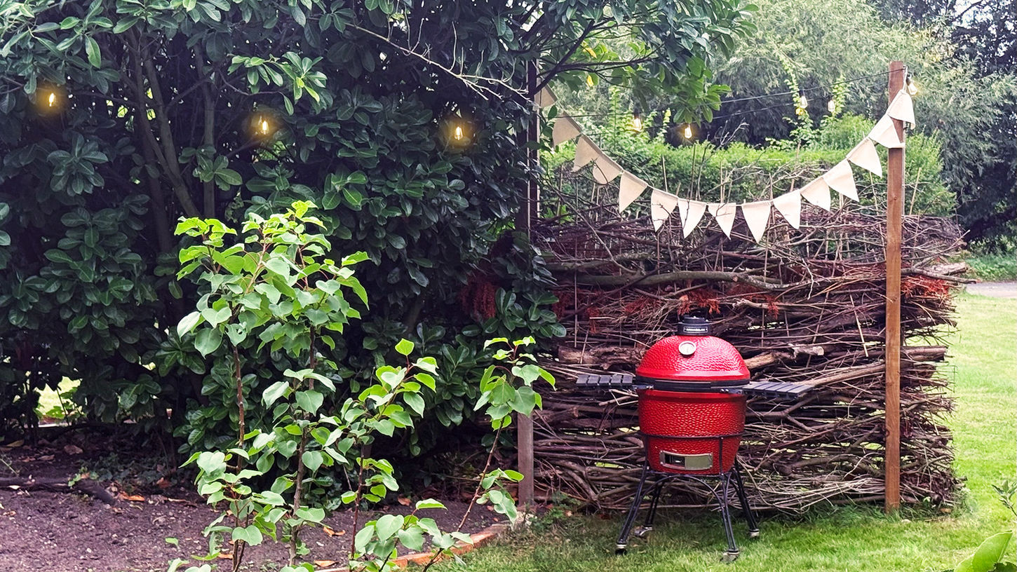 BBQ area, decorated with bunting and outdoor string lights and handmade sticks wall privacy panel.