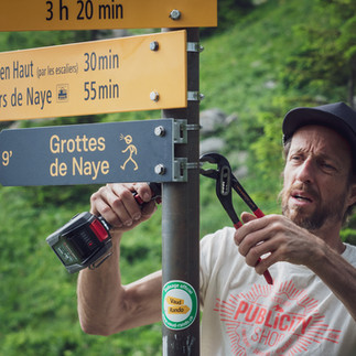 Une personne installe la signalétique directionnelle aux Rochers de Naye
