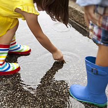 _Boy-and-sister-wearing-rubber-boots-looking-down-at-in-rain-puddle