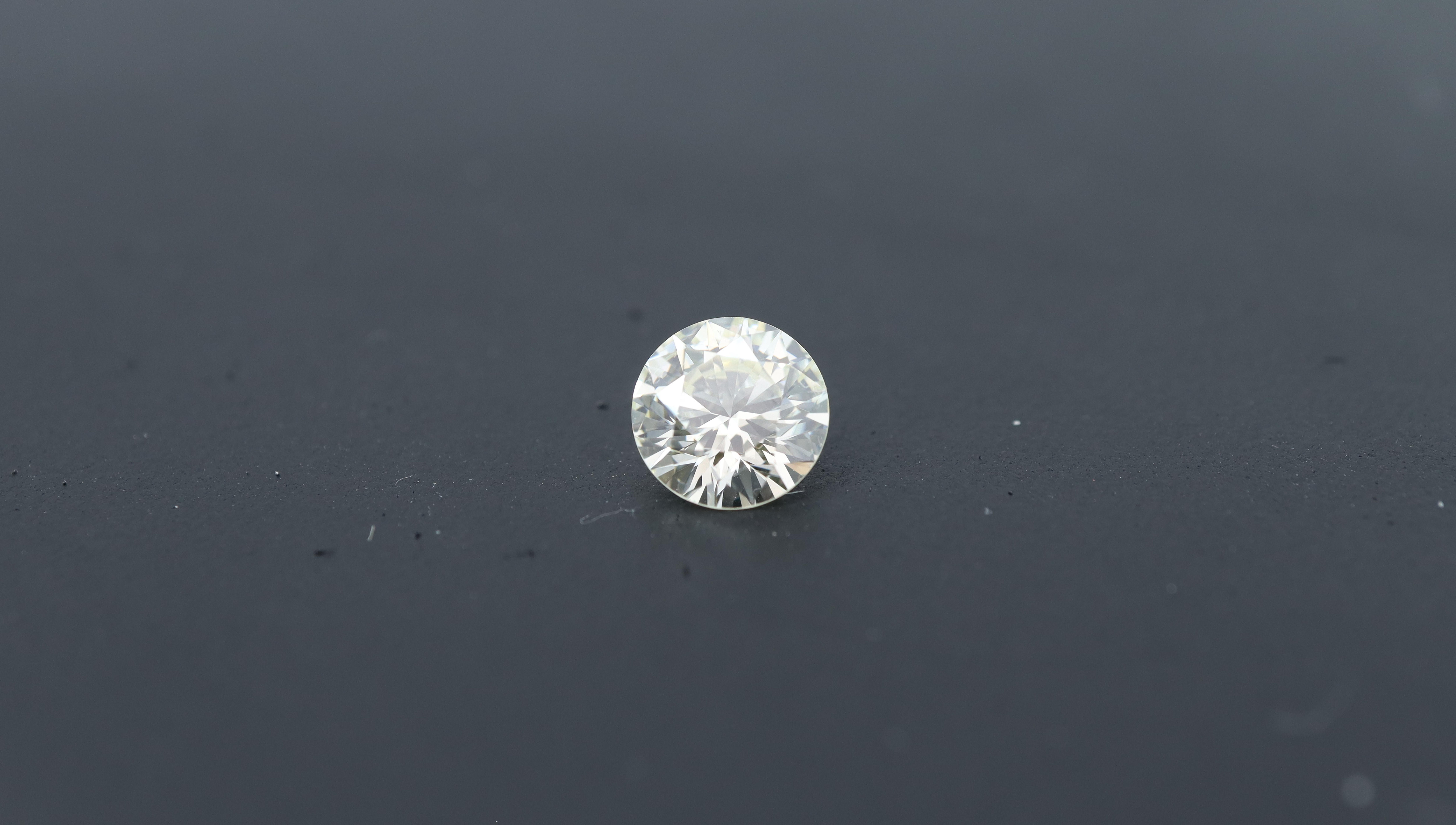 Photo of a natural round polished diamond with 0.66ct, a premium size, ideal for jewelry making, with a neutral background.