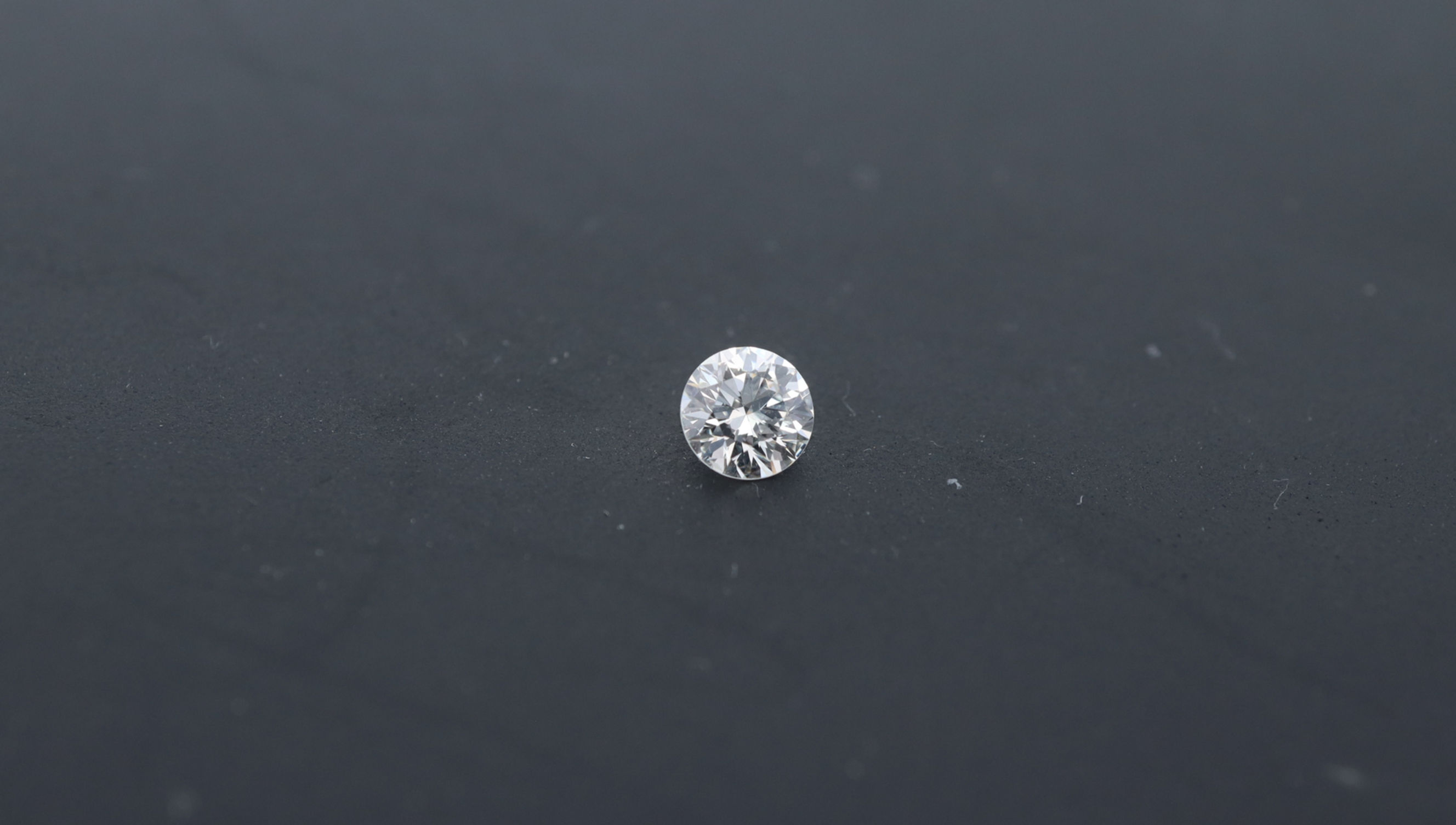 Photo of a round diamond with a neutral dark background. this stone was certified by a gemmological lab color E clarity SI1