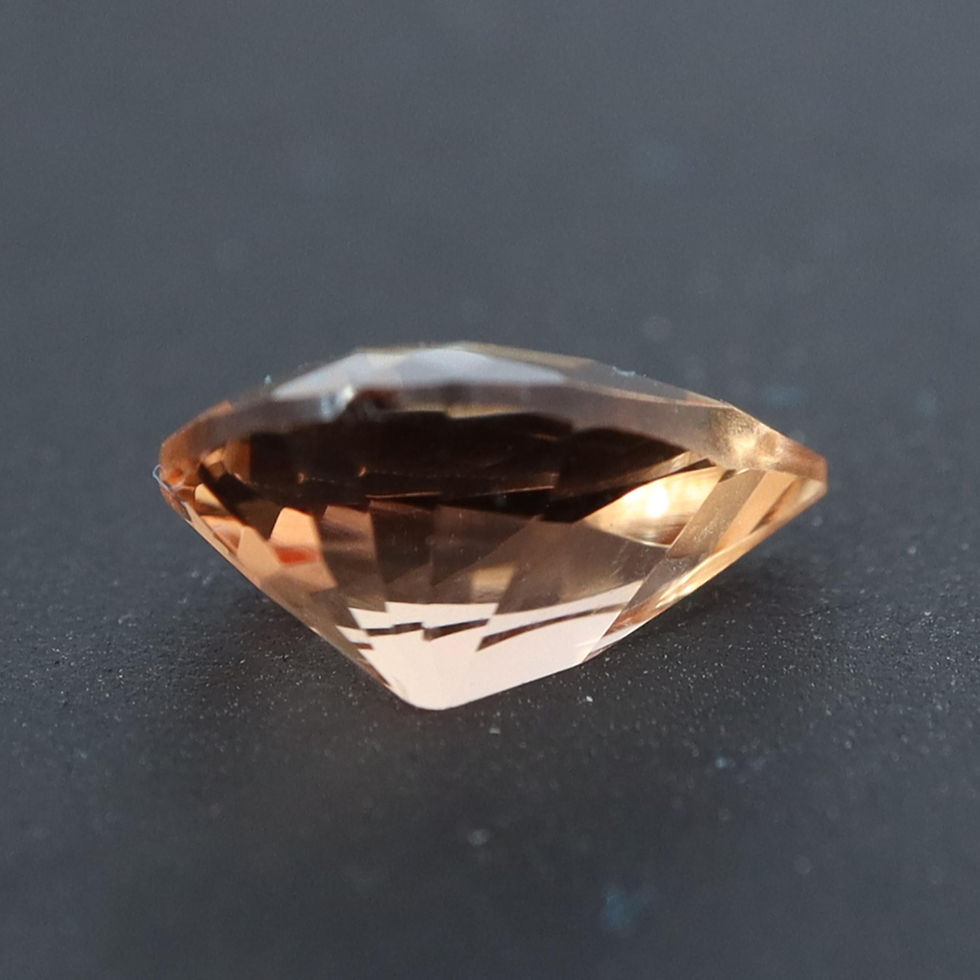 Zoomed pavilion vie of an Imperial Topaz, precision cut, showing the polished girdle and the precision alignement of all its factes.