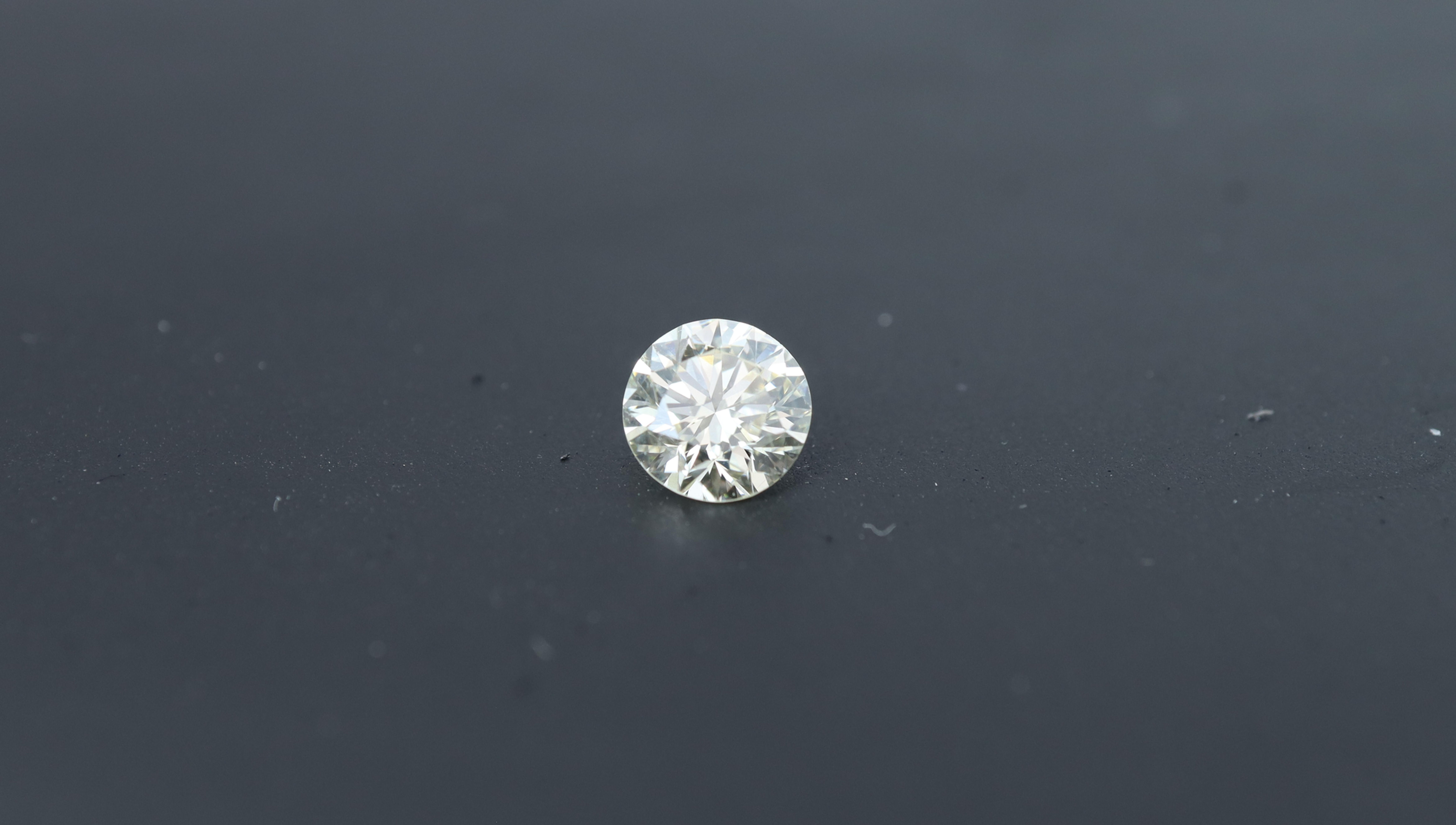 Photo of a natural round polished diamond with 0.62ct, a premium size, ideal for jewelry making, with a neutral background.