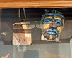 Open drawer with items under glass - metal hand mirror and an African tribal mask.