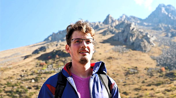 Traveler with backpack overlooking mountains, budget travel lifestyle