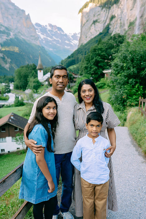 Family portrait on a scenic Lauterbrunnen village path with the church and alpine mountains in the background.