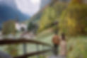 Couple photoshoot in Lauterbrunnen, Switzerland: two people holding hands on a path above the valley with autumn colors and snow-capped mountains.