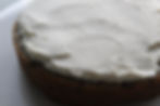 A round cake with oreos topped with smooth white icing on a white plate, creating a simple and rustic presentation.