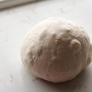the dough shaped into a smooth ball with butter visible underneath