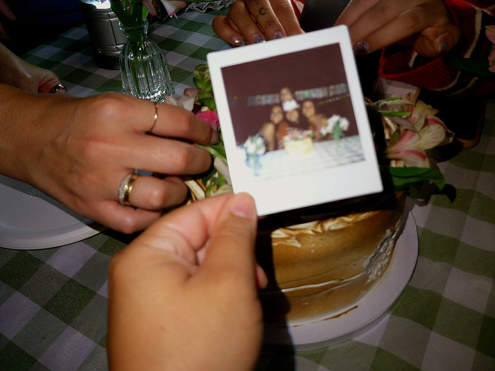 Woman taking a mirror selfie in a bedroom, wearing a blue green sequined dress with a sun design, jewelry, and orange cat eye nails.