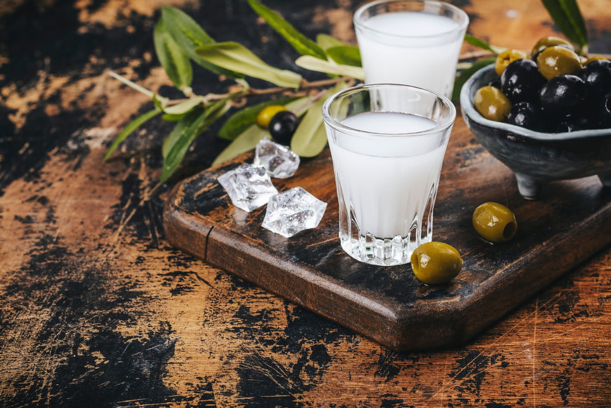 Traditional greek vodka ouzo and marinated olives on rustic wooden table.jpg