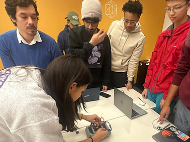 Rice Robotics students surrounding girl fixing robot prototype