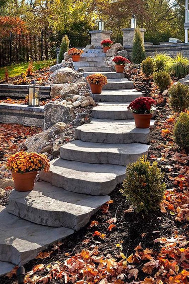 Rustic round stone steps leading down with an autumn leaf strewn garden