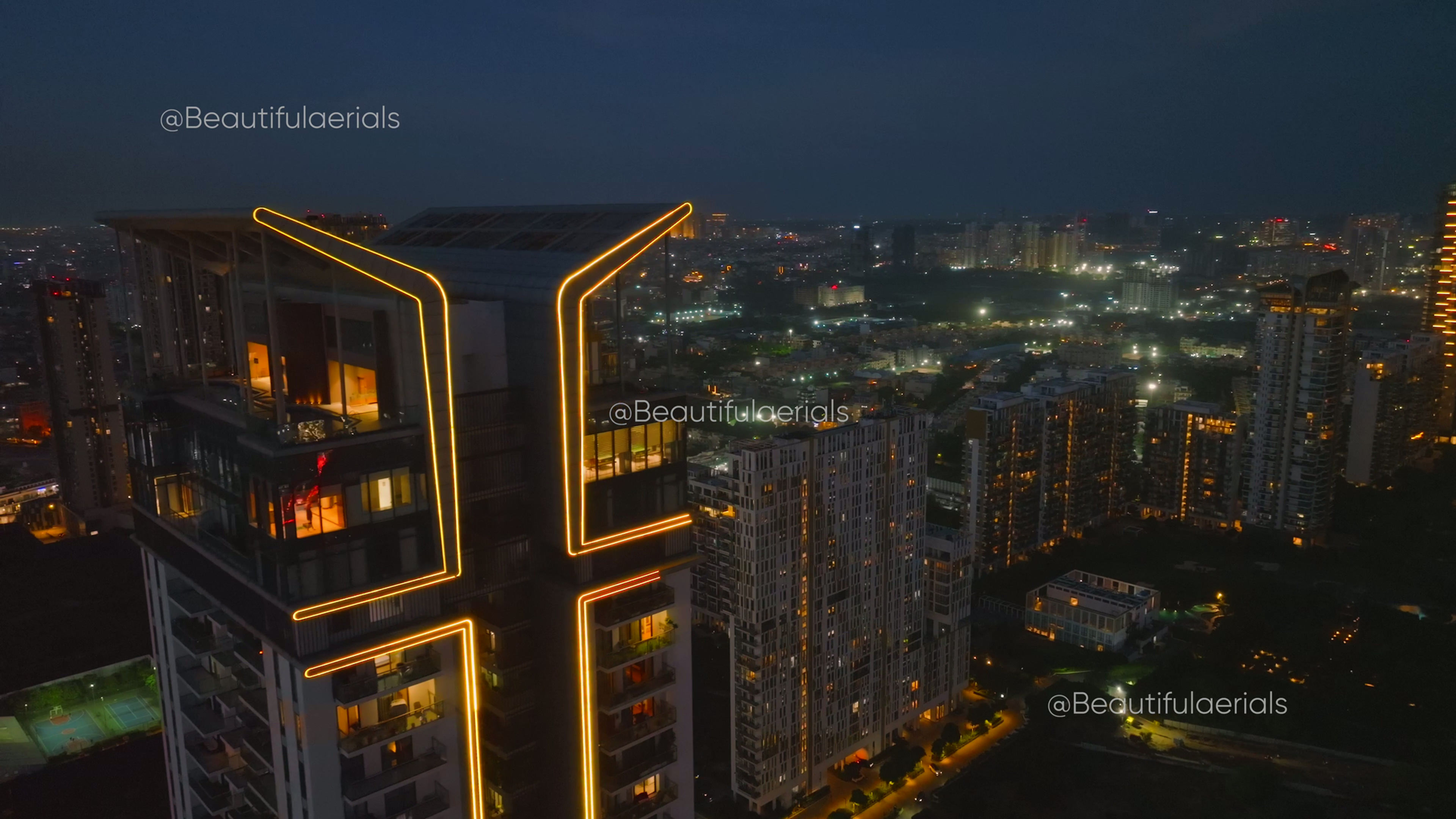 Aerial reveal shot of Gurgaon's lit cityscape during twilight on a clear day