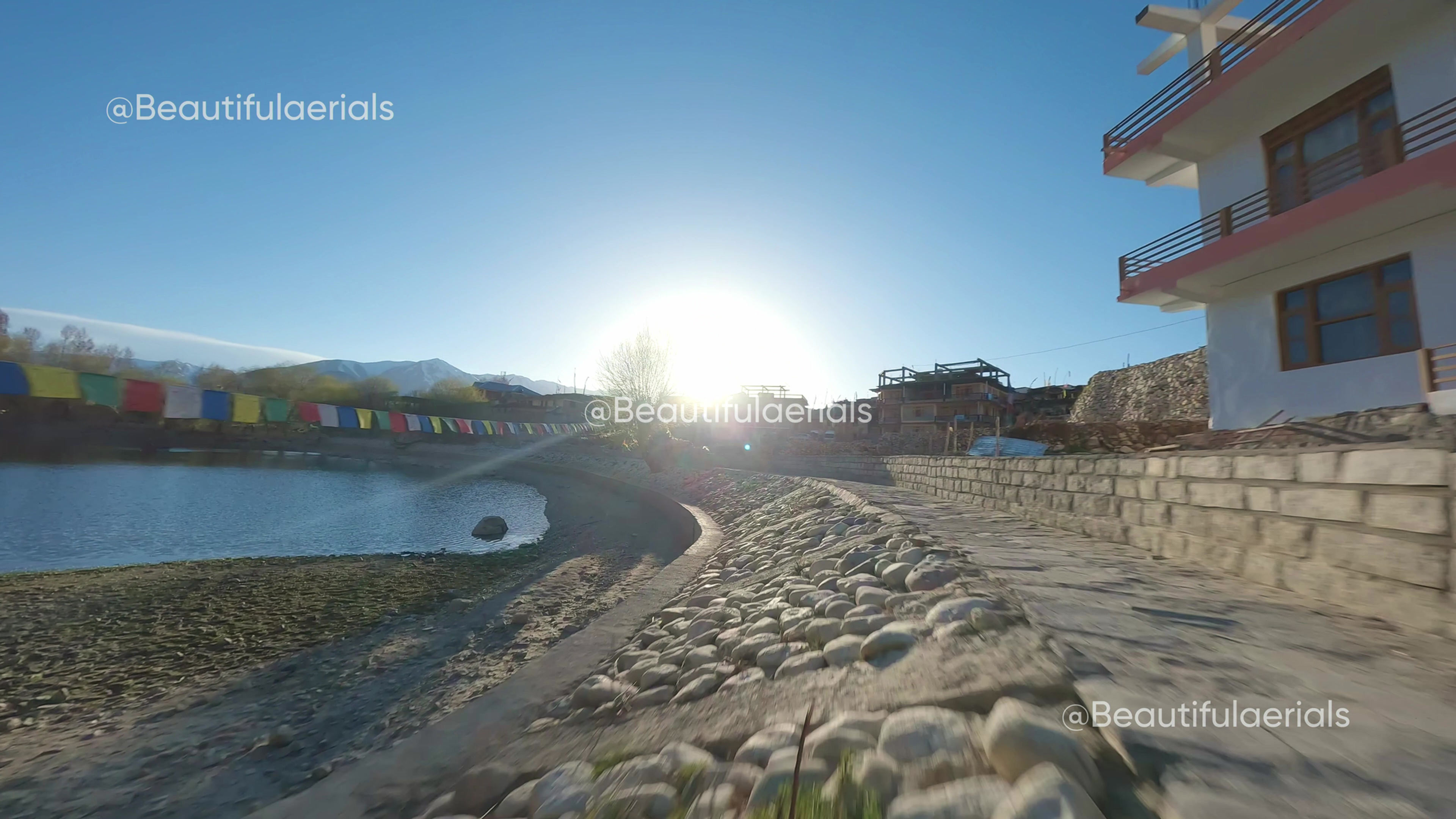 Cinematic low fly fpv shot of Nako village, reveal through flags and name post