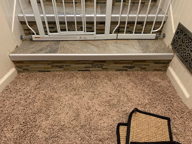 Bottom Step in the basement with view of tiled top and mosaic riser