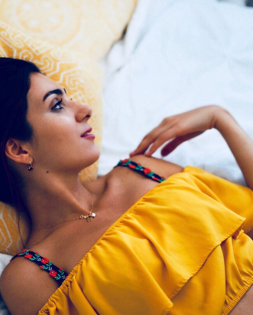 Miniatura: Woman wearing bra with flower straps laying down. Blue floral bra straps paired with yellow off the shoulder top.