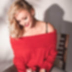 Thumbnail: Woman wearing bra with gold pyramid studs on black faux-suede, in red off the shoulder sweater top.