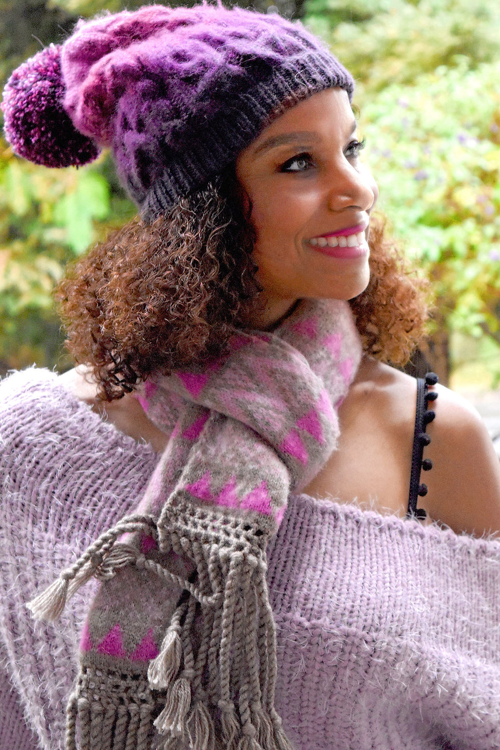 Miniatura: Woman wearing black bra straps with pompoms in a light purple knit off the shoulder top and scarf, close-up of one shoulder.