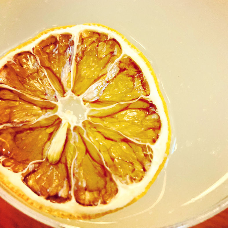 Caramelized grapefruit half sliced into segments on a white background