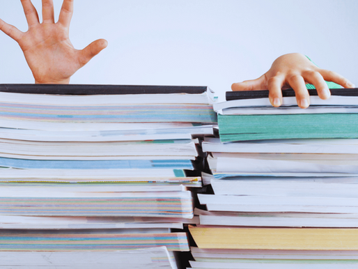 two human hands atop a stack of papers, symbolising an overwhelmed business owner