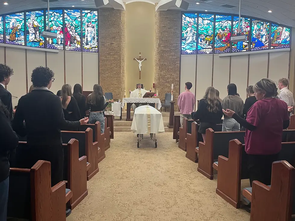 Personas en ceremonia religiosa en iglesia con vitrales coloridos. Un sacerdote en el altar oficia el ritual. Ambiente solemne.