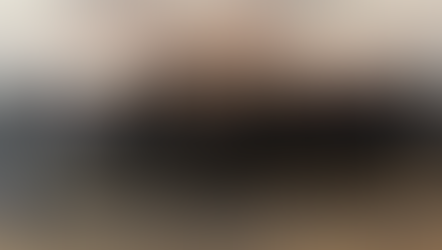 Grupo de hombres sonrientes, muchos con collares de cruces, posan en una sala. Fondo gris y suelo de alfombra. Ambiente formal.