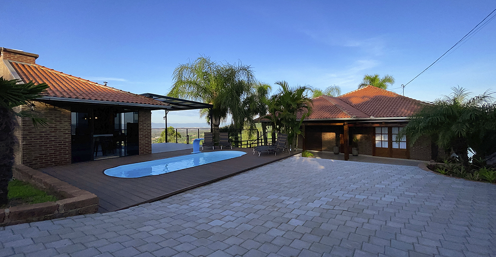 Vista da Casa Refúgio com a piscina e o quiosque a frente, a casa aos fundos, e os vales e montanhas mais distantes.