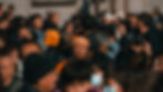 行き交う人混みの中、オレンジの民族衣装を身につけた中国人の男性が立っている