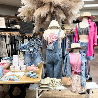 Creative summer retail display showcasing vacation-ready outfits and travel-inspired decor.